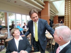A man in a suit engaging with two seated individuals in a professional setting.